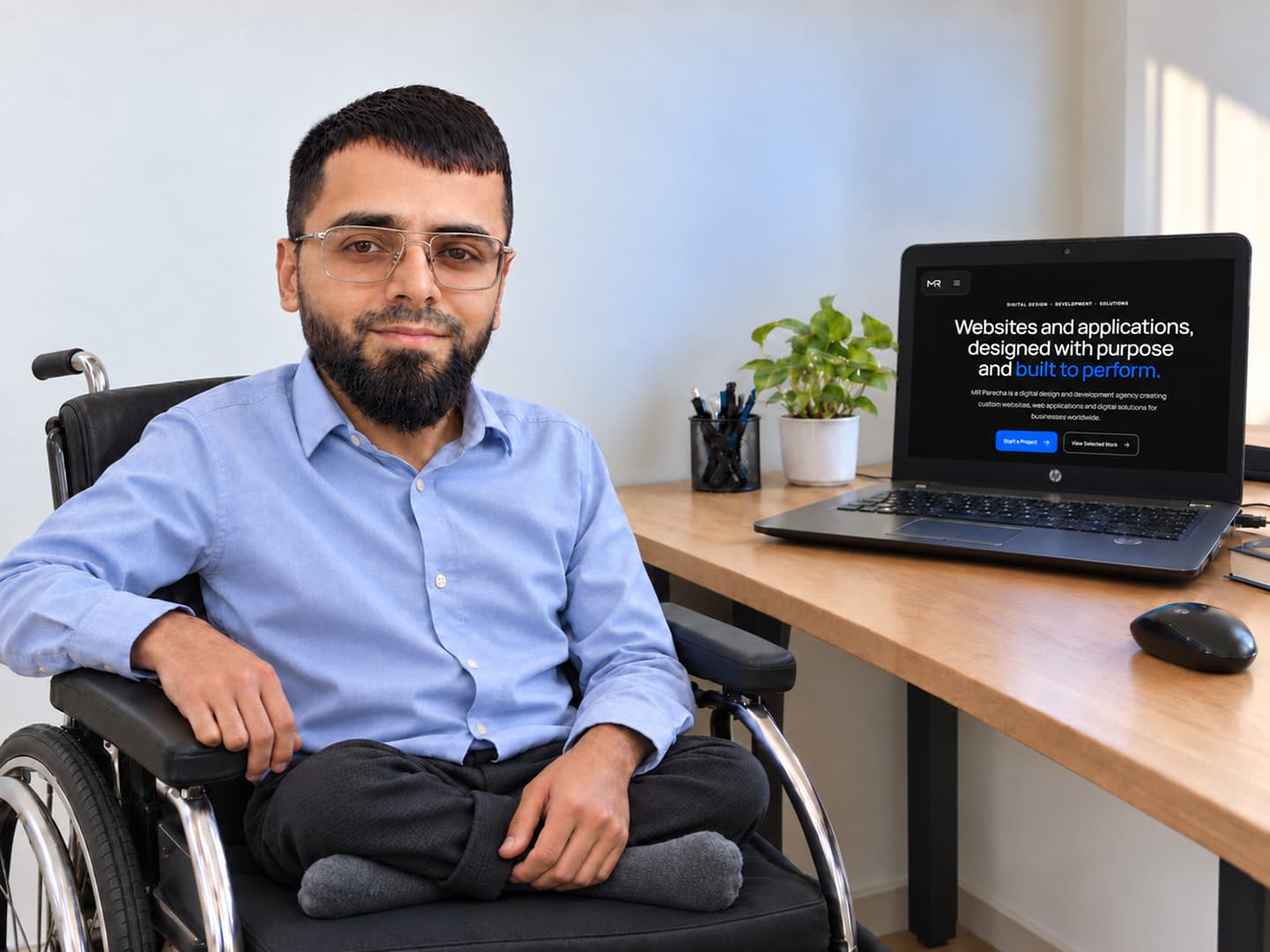 MR Paracha founder at his workspace beside a laptop displaying the MR Paracha website.